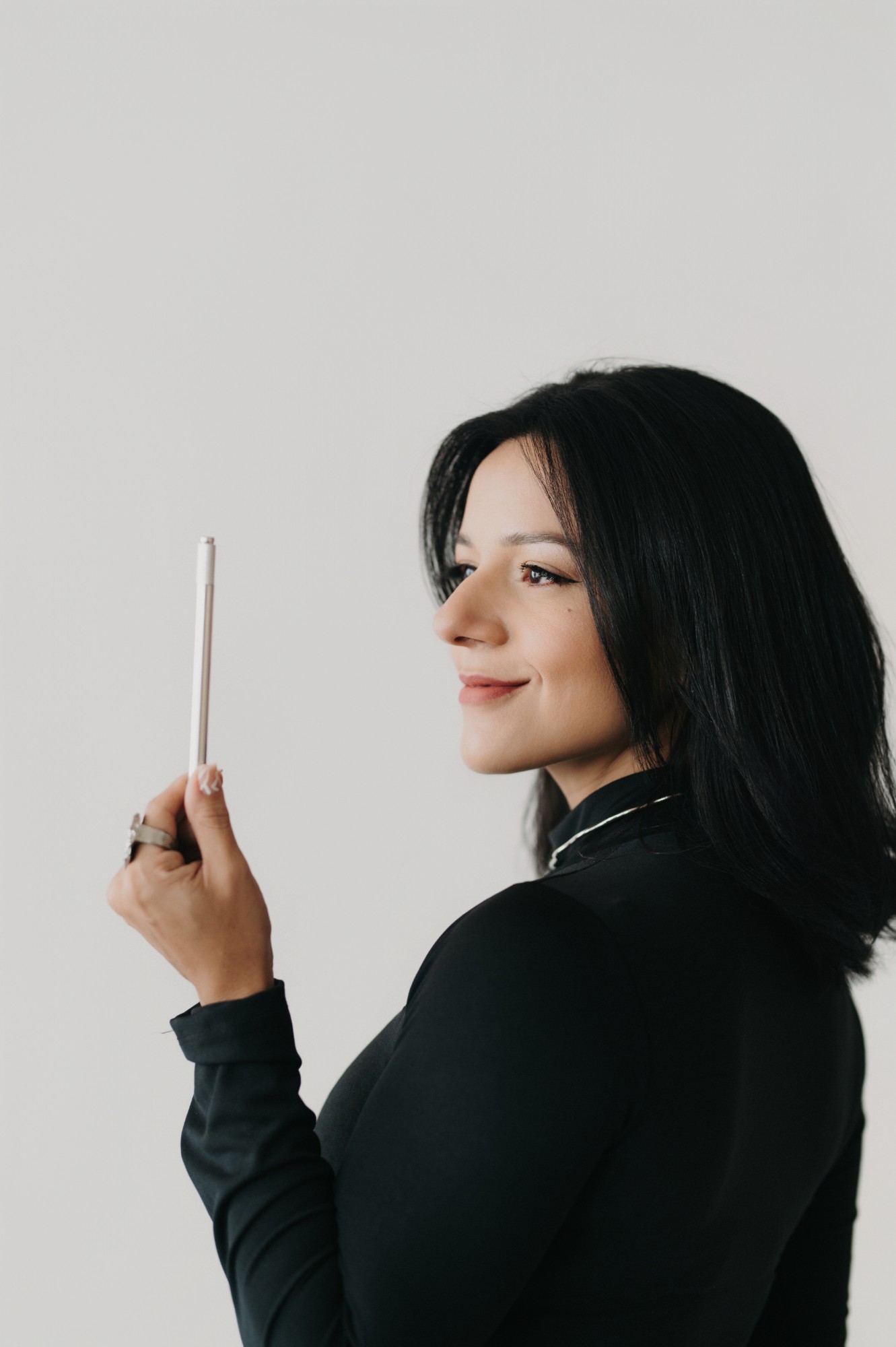Nicole Amorim de perfil, sorrindo, segurando a caneta de tebori